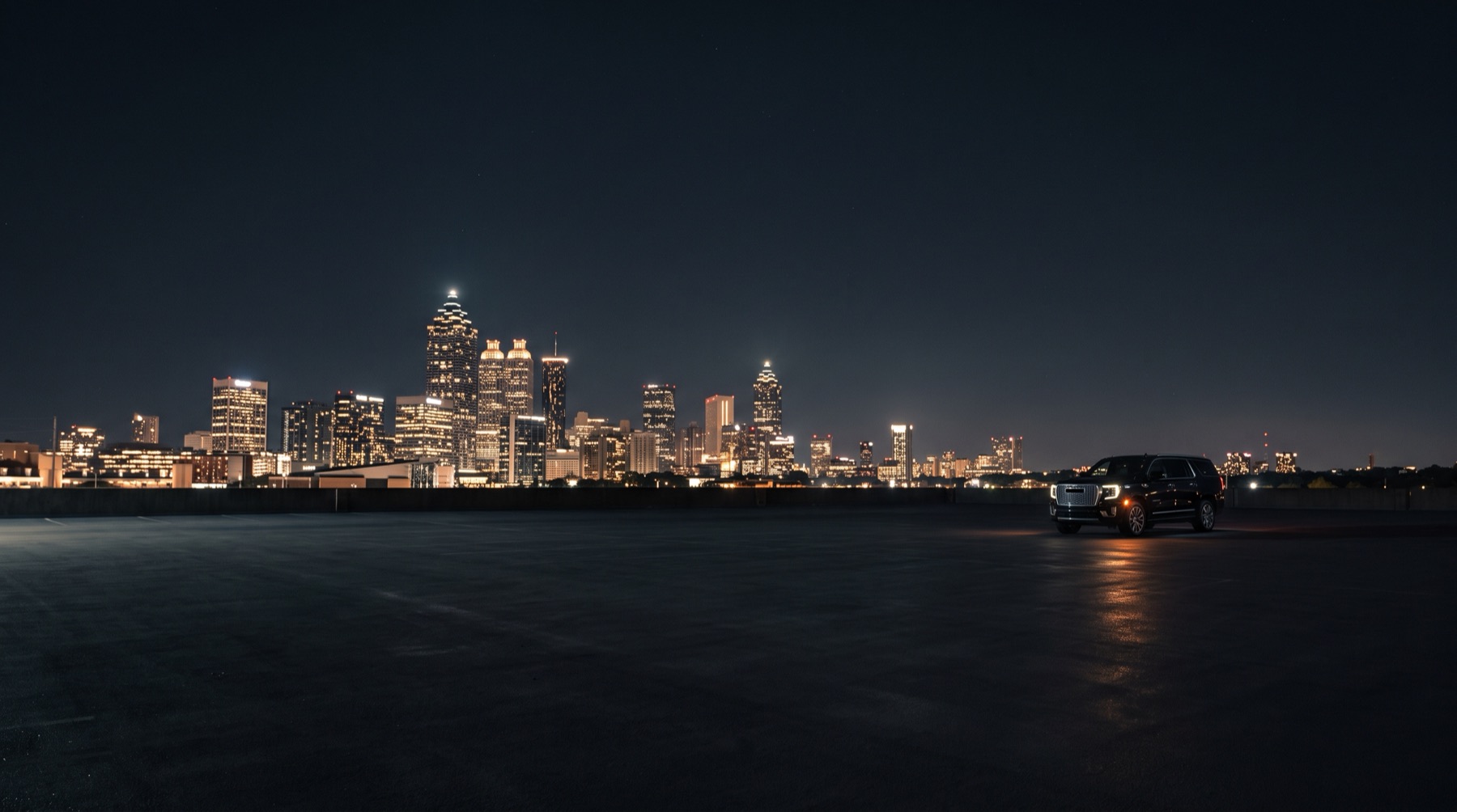 Luxivo's Yukon XL Denali parked against the Atlanta skyline at night